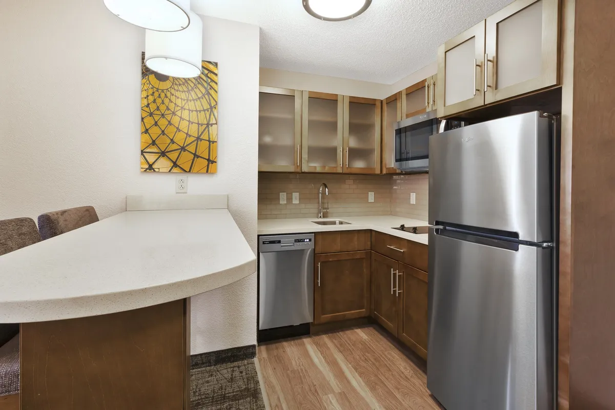 A welcoming kitchen scene featuring a modern kitchen counter with stainless steel appliances and stylish wall art. The layout includes a stove, oven, and dishwasher, as well as ample countertop space for preparing meals or snacks.