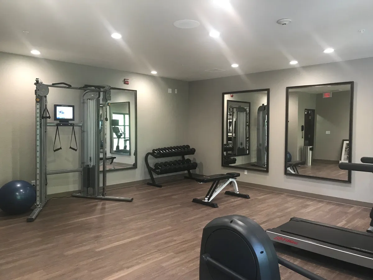 The hotel’s fitness center is showcased here, with a weight machine, dumbbell rack, exercise ball, treadmill, and large mirrors. The motivational atmosphere invites guests to recharge after work.