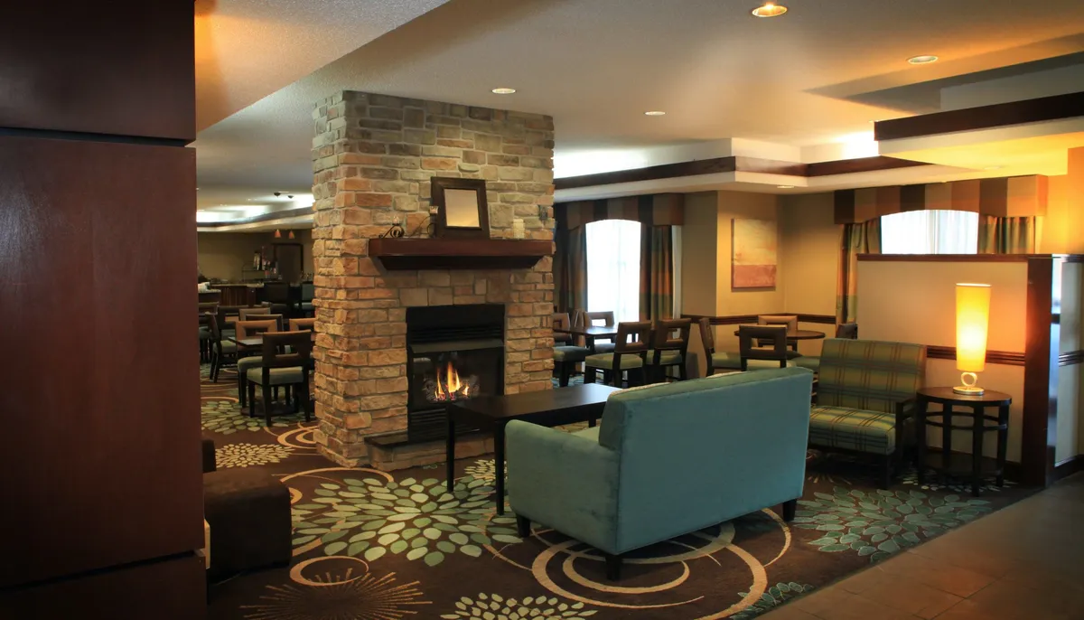 This interior image highlights a cozy living area with a stone fireplace, comfortable seating, and a decorative rug. The arrangement suggests a space ideal for socializing, relaxing, or gathering for activities such as movie nights or games.